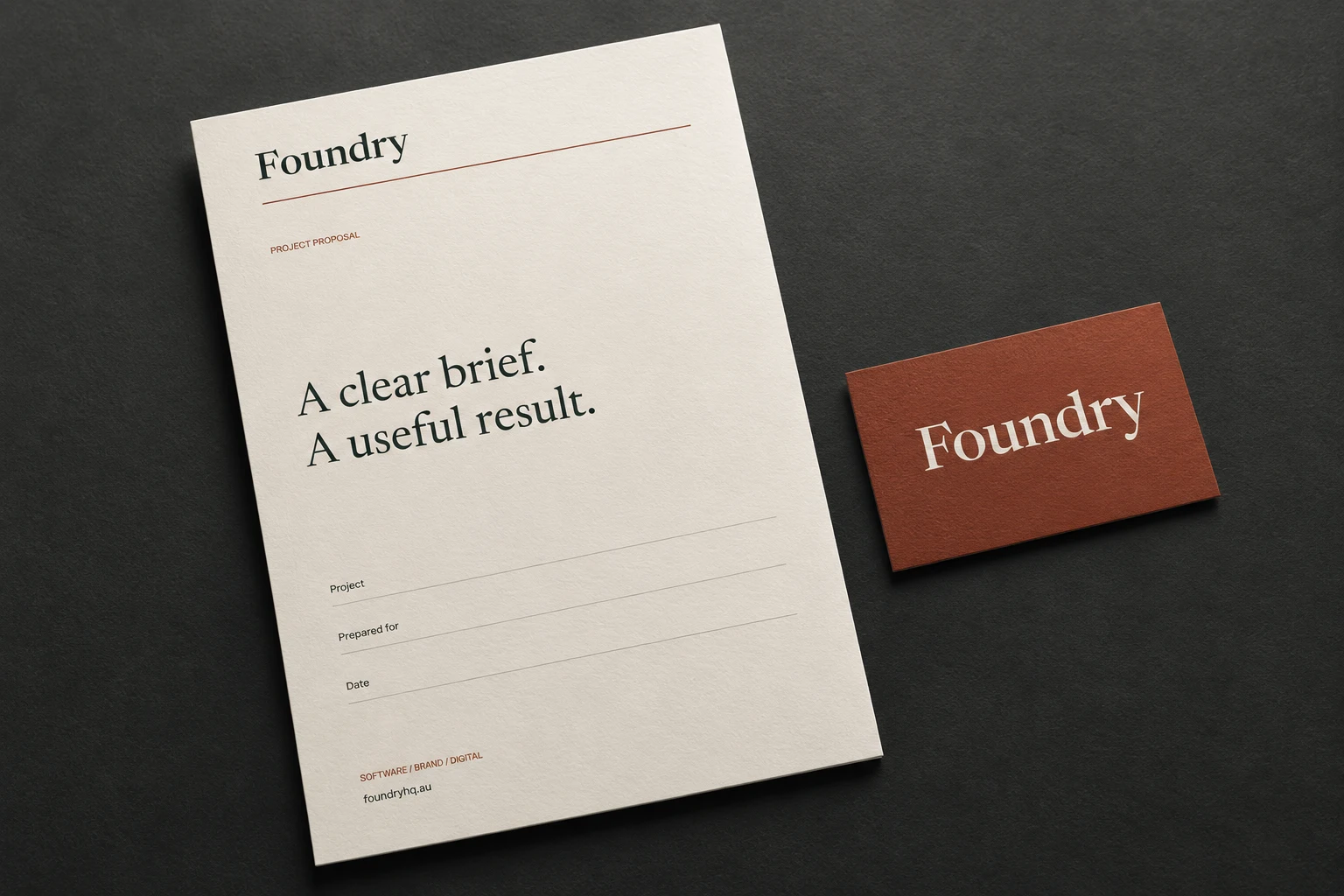 Digital mockup of Foundry’s ivory proposal cover and rust wordmark card on a graphite surface.